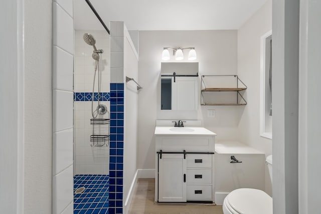 bathroom with a tile shower, vanity, toilet, and wood-type flooring