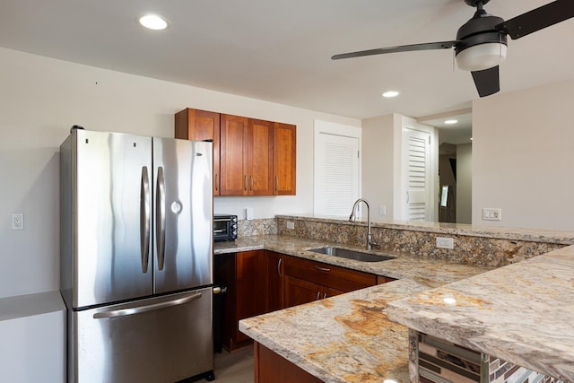 kitchen with kitchen peninsula, stainless steel refrigerator, ceiling fan, and sink