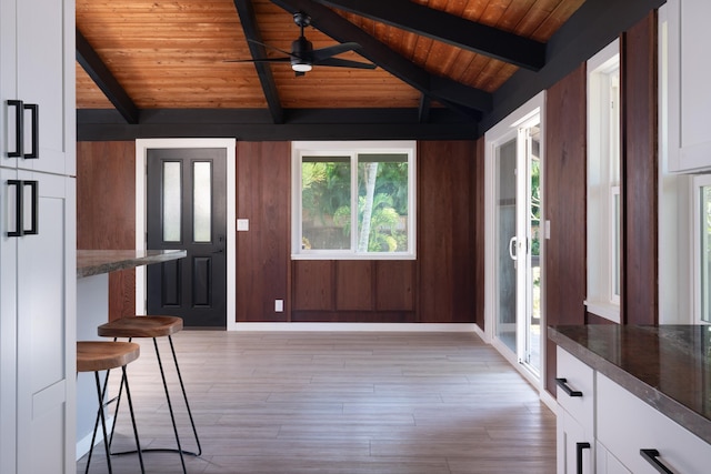 foyer entrance featuring wood ceiling, wood walls, lofted ceiling with beams, and light wood-type flooring