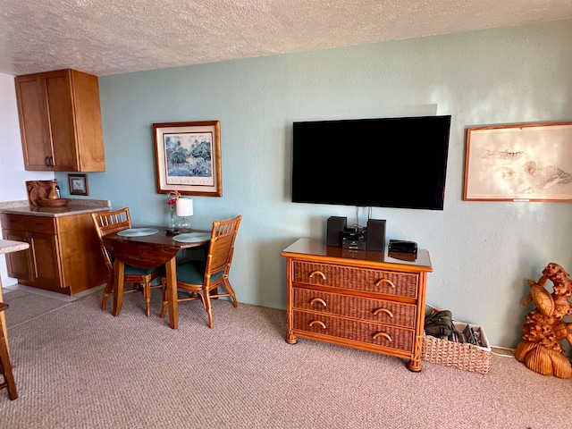 carpeted dining room featuring a textured ceiling