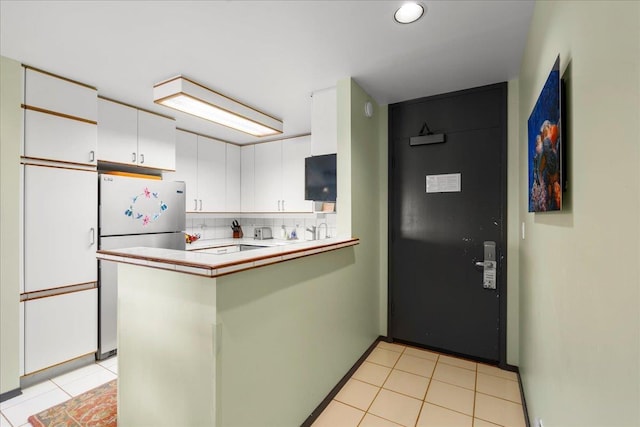 2661 Kekaa Dr Unit L-202, Lahaina, HI 96761 - kitchen featuring freestanding refrigerator, white cabinetry, a peninsula, light tile patterned floors, and backsplash