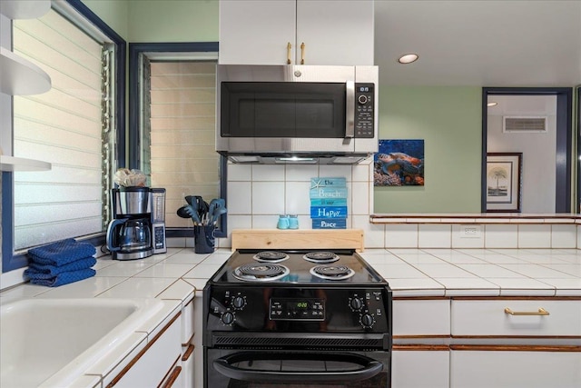 2661 Kekaa Dr Unit L-202, Lahaina, HI 96761 - kitchen featuring stainless steel microwave, black electric range, tile countertops, white cabinetry, and backsplash