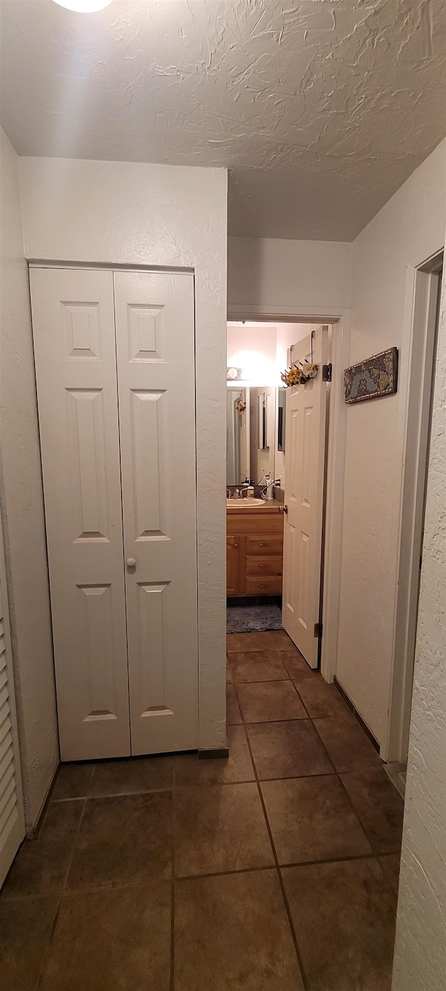 hall featuring dark tile patterned floors and a textured ceiling