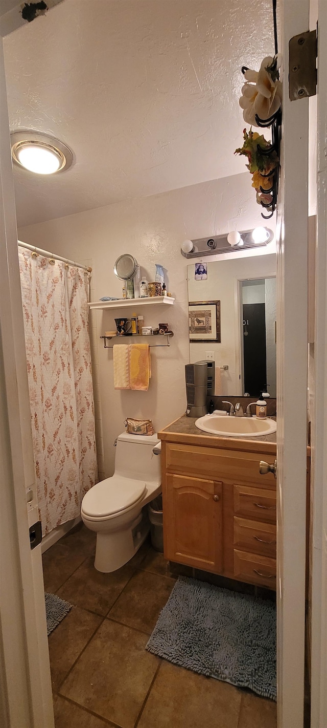 bathroom with curtained shower, vanity, toilet, and tile patterned floors