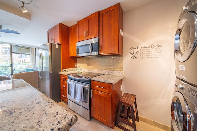 kitchen with light stone countertops, stainless steel appliances, backsplash, stacked washer / dryer, and a wall unit AC