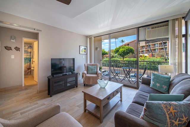 living room featuring expansive windows, light hardwood / wood-style floors, an AC wall unit, and ceiling fan