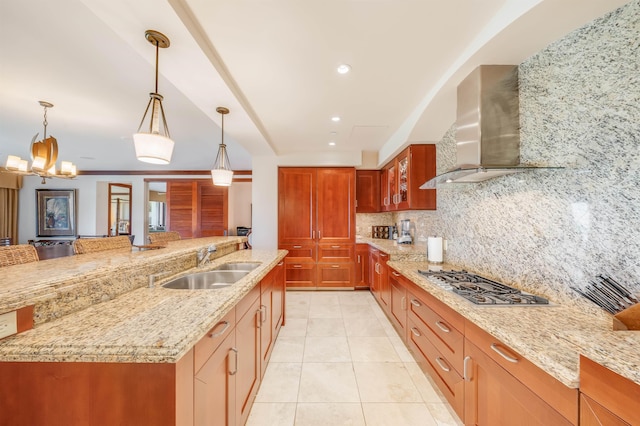 kitchen with tasteful backsplash, decorative light fixtures, stainless steel gas cooktop, wall chimney range hood, and sink