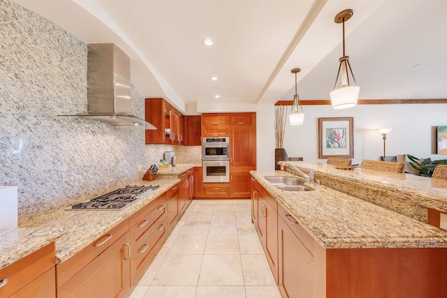 kitchen featuring decorative light fixtures, wall chimney range hood, sink, stainless steel appliances, and light stone counters