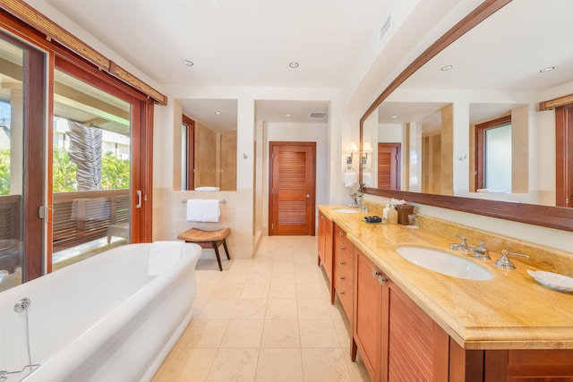 bathroom with tile patterned flooring, a tub to relax in, and vanity