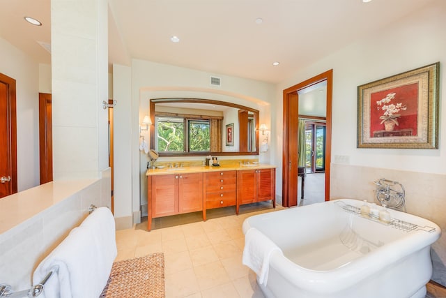 bathroom featuring plenty of natural light, a tub to relax in, vanity, and tile patterned flooring