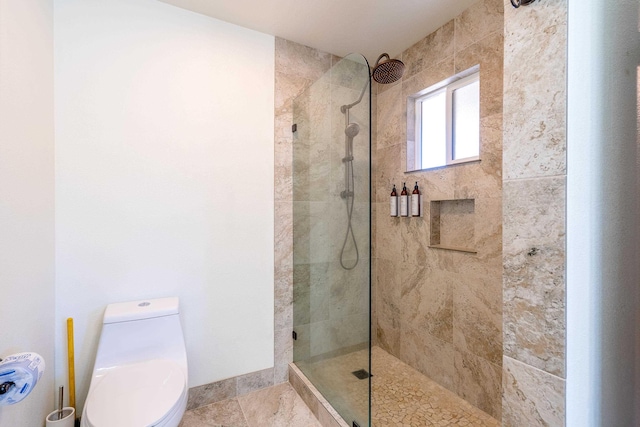 bathroom featuring tiled shower and toilet