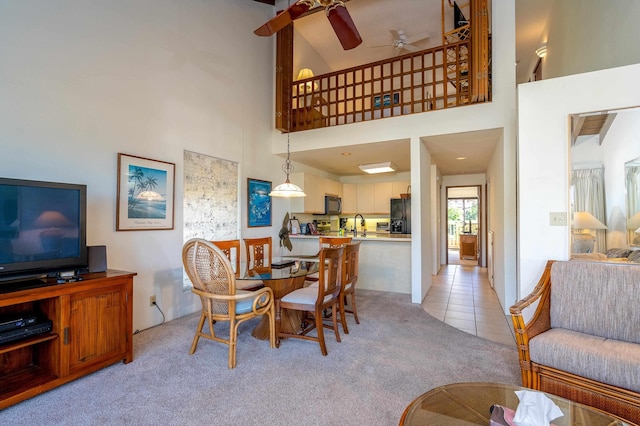 carpeted dining area featuring high vaulted ceiling, ceiling fan, and sink