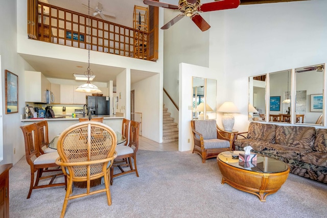 living room with light carpet, a towering ceiling, and ceiling fan