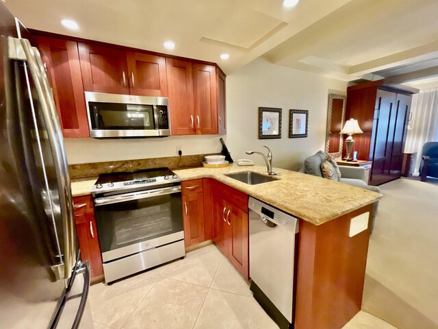 kitchen with kitchen peninsula, appliances with stainless steel finishes, sink, a tray ceiling, and light tile patterned flooring