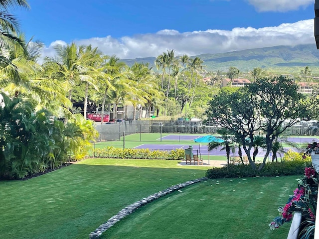 view of home's community with a mountain view, tennis court, and a lawn