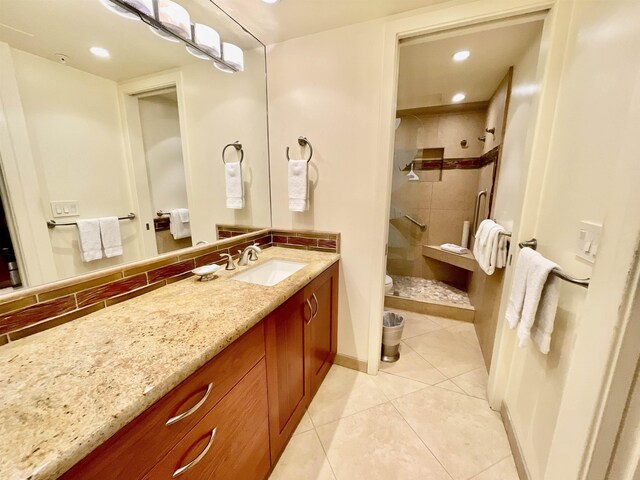 bathroom featuring tile patterned floors, tiled shower, vanity, and toilet