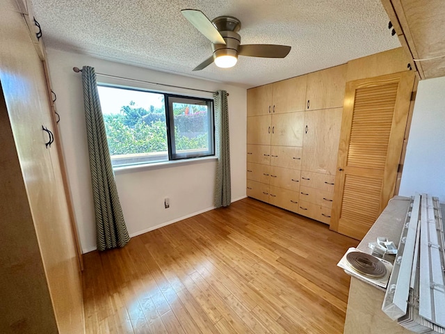 unfurnished bedroom with ceiling fan, a textured ceiling, and light wood-type flooring