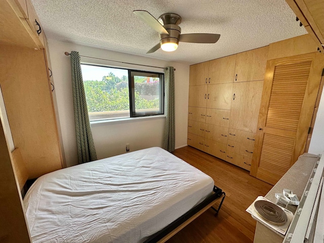 bedroom featuring hardwood / wood-style floors, a textured ceiling, and ceiling fan