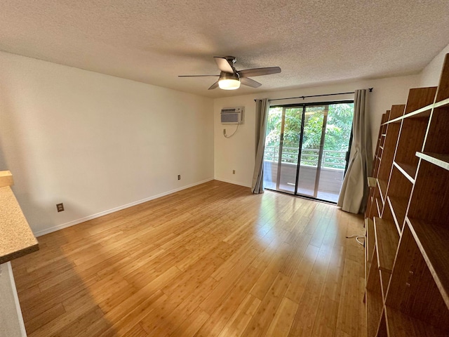 spare room with a wall mounted air conditioner, light hardwood / wood-style flooring, a textured ceiling, and ceiling fan