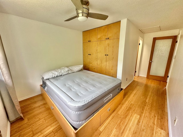 bedroom featuring light hardwood / wood-style flooring, a textured ceiling, and ceiling fan