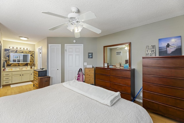 bedroom featuring a textured ceiling, ceiling fan, light wood finished floors, and connected bathroom