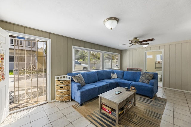 living area with light tile patterned floors, ceiling fan, and baseboards