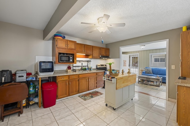 kitchen with light countertops, brown cabinetry, ceiling fan, a textured ceiling, and built in microwave