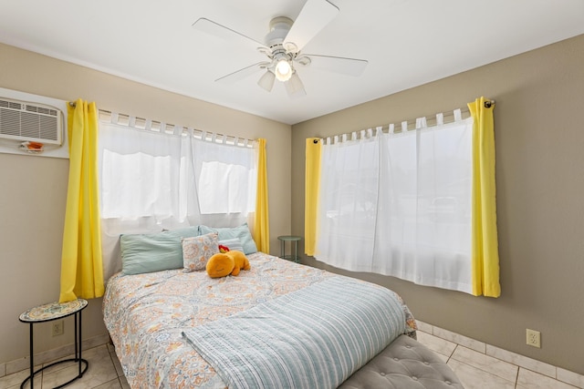 tiled bedroom with ceiling fan, multiple windows, baseboards, and a wall mounted air conditioner