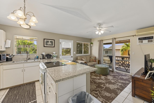 kitchen with light tile patterned floors, white range with electric stovetop, a wall unit AC, stainless steel microwave, and a sink