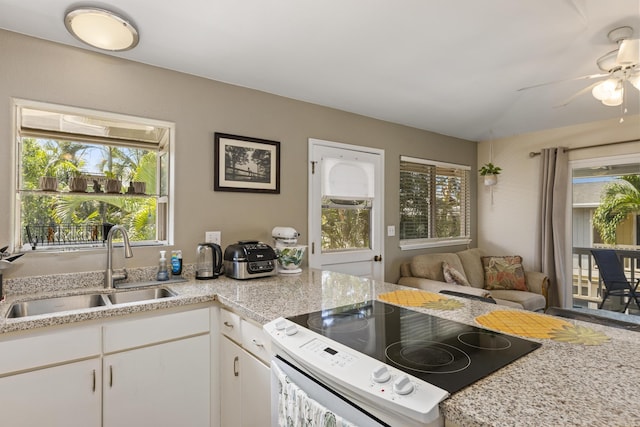 kitchen featuring white range with electric stovetop, open floor plan, white cabinetry, vaulted ceiling, and a sink