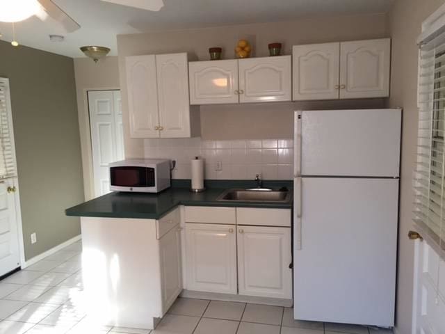 kitchen with ceiling fan, a sink, white cabinetry, freestanding refrigerator, and dark countertops