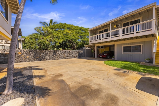 view of patio with a balcony, fence, a carport, and concrete driveway