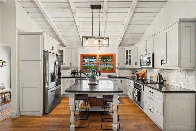 kitchen with appliances with stainless steel finishes, dark countertops, wood ceiling, tasteful backsplash, and glass insert cabinets