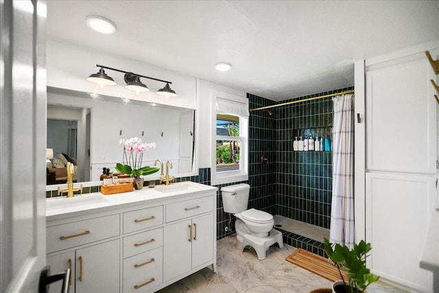 full bath featuring toilet, a tile shower, marble finish floors, and double vanity