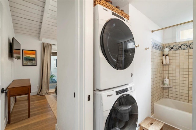 clothes washing area featuring stacked washer / drying machine and wood finished floors