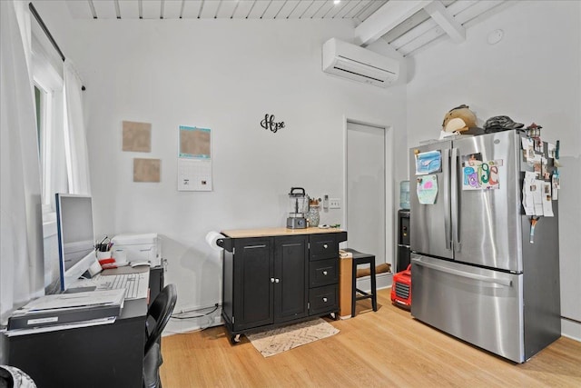 kitchen featuring freestanding refrigerator, dark cabinets, light wood-style floors, a wall unit AC, and an office area