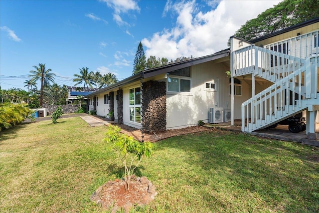 view of home's exterior with a lawn, stairway, a deck, and central AC