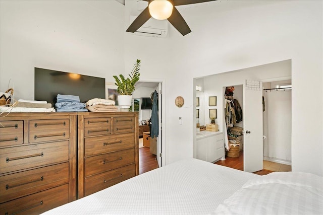 bedroom featuring a spacious closet, a closet, a towering ceiling, ceiling fan, and a wall mounted air conditioner