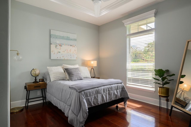 bedroom with baseboards, ornamental molding, a tray ceiling, and dark wood-style floors