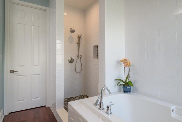 full bathroom featuring a garden tub, wood finished floors, and a tile shower