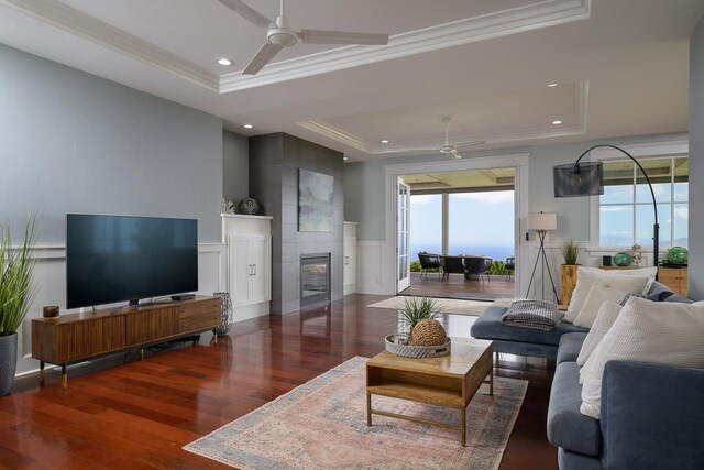 living room featuring ceiling fan, wood finished floors, a raised ceiling, and crown molding