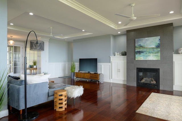 living area featuring a ceiling fan, hardwood / wood-style flooring, a raised ceiling, and crown molding
