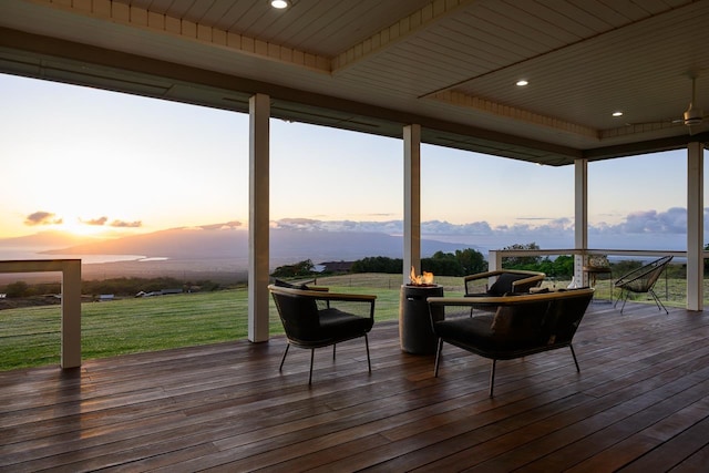 deck at dusk featuring a lawn and a mountain view