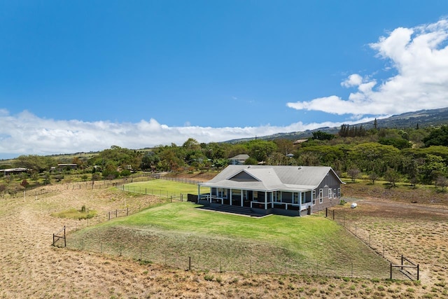back of property with a rural view, fence private yard, a sunroom, and a yard