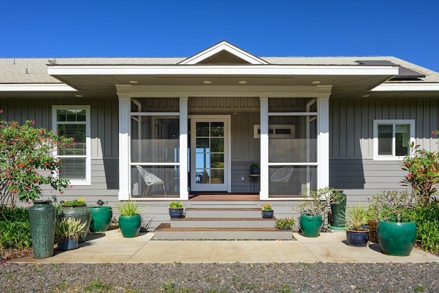 entrance to property with roof with shingles, a porch, and board and batten siding