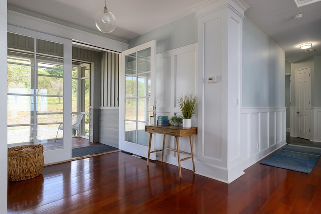 doorway featuring hardwood / wood-style flooring, a decorative wall, and wainscoting