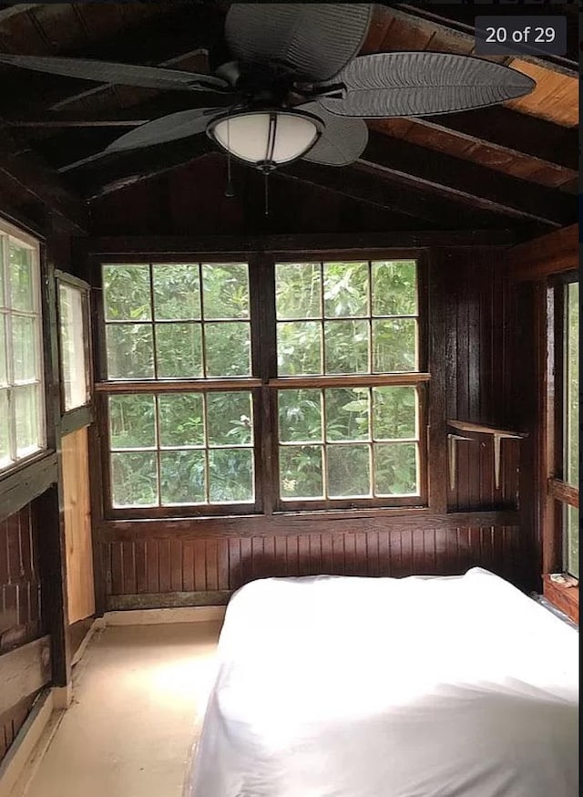 bedroom with wood walls, vaulted ceiling, and multiple windows