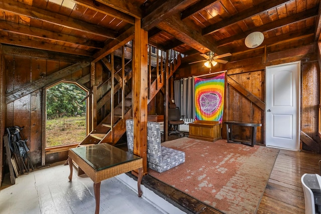 interior space featuring ceiling fan, wooden walls, wood-type flooring, wooden ceiling, and beamed ceiling