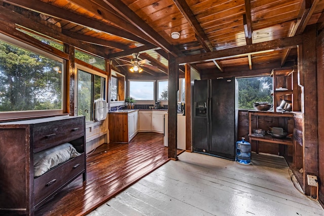 interior space with a wealth of natural light, black fridge with ice dispenser, and wood ceiling