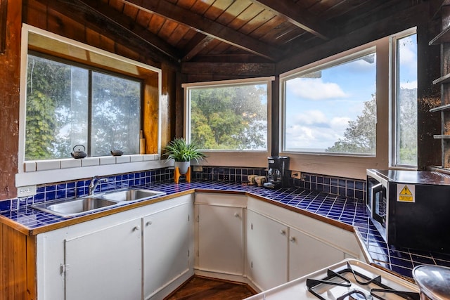 kitchen featuring white cabinetry, tile counters, and sink